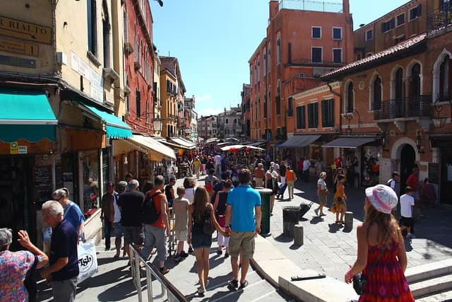 Early morning view of the Rialto market in Venice with stalls and the Grand Canal.